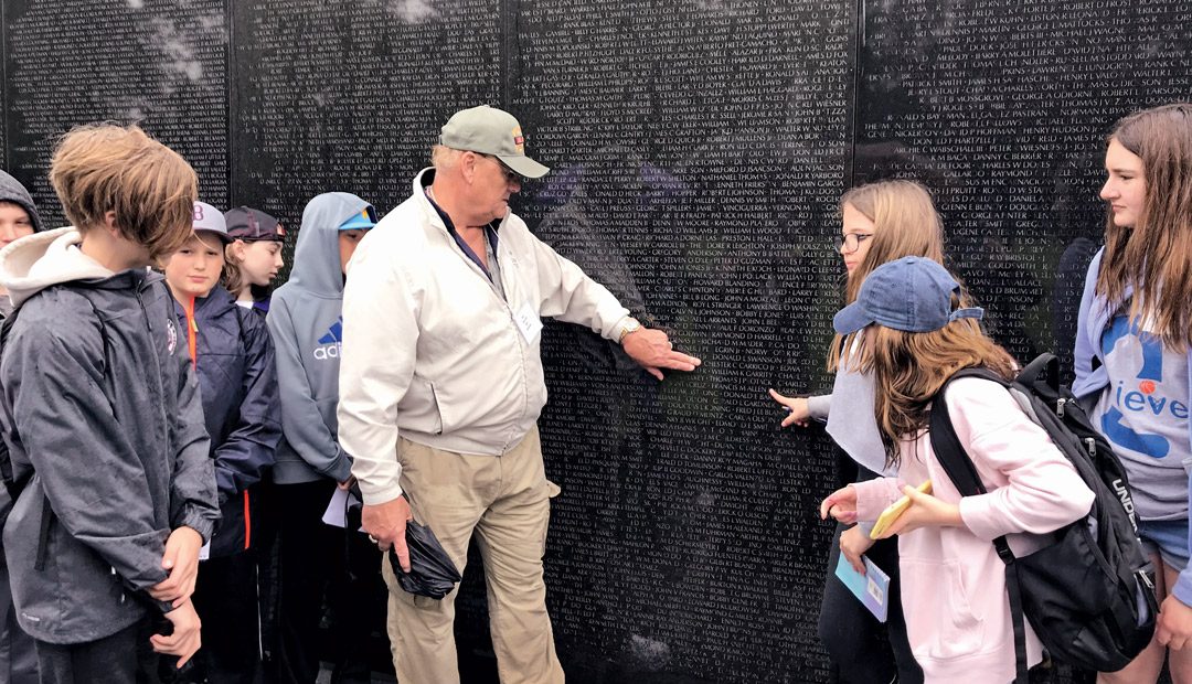 Veteran Stands at Memorial with Students